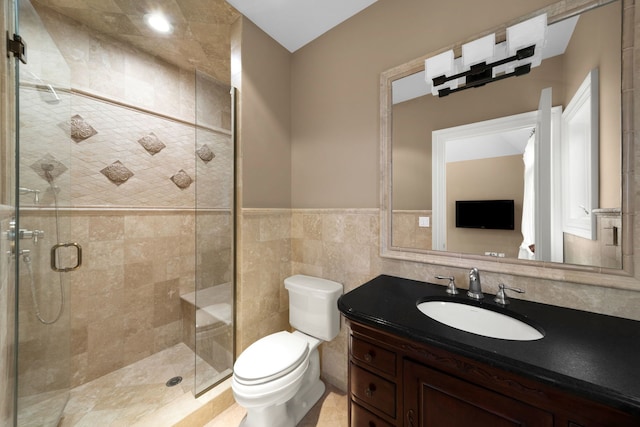 bathroom featuring a stall shower, wainscoting, toilet, vanity, and tile walls