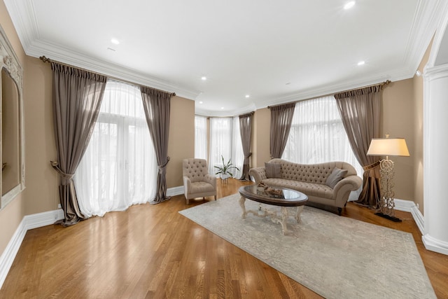 living area with decorative columns, recessed lighting, ornamental molding, wood finished floors, and baseboards