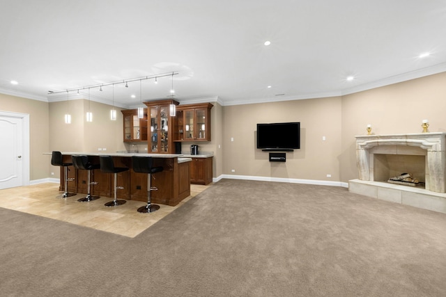 bar featuring baseboards, a tile fireplace, light colored carpet, crown molding, and indoor wet bar