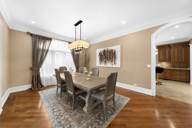 dining room with light wood-style floors, baseboards, and crown molding