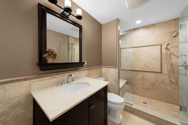 full bathroom featuring a wainscoted wall, tile walls, toilet, a stall shower, and vanity