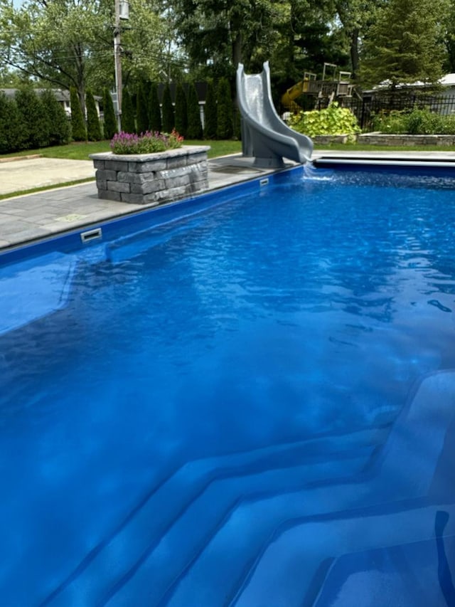 view of pool featuring a fenced in pool, a water slide, and fence