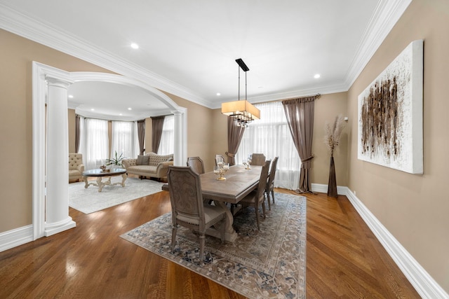 dining space with plenty of natural light, decorative columns, crown molding, and wood finished floors