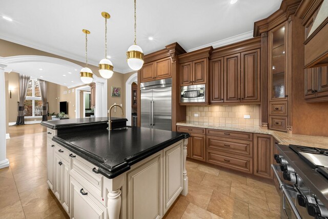 kitchen featuring tasteful backsplash, decorative columns, arched walkways, glass insert cabinets, and built in appliances