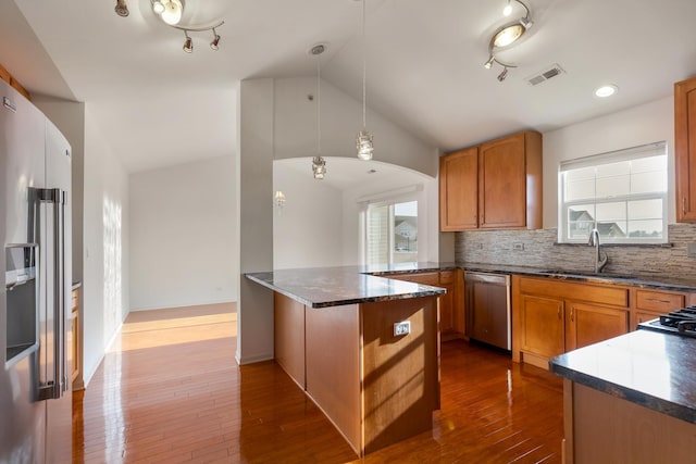 kitchen featuring lofted ceiling, sink, appliances with stainless steel finishes, hanging light fixtures, and kitchen peninsula