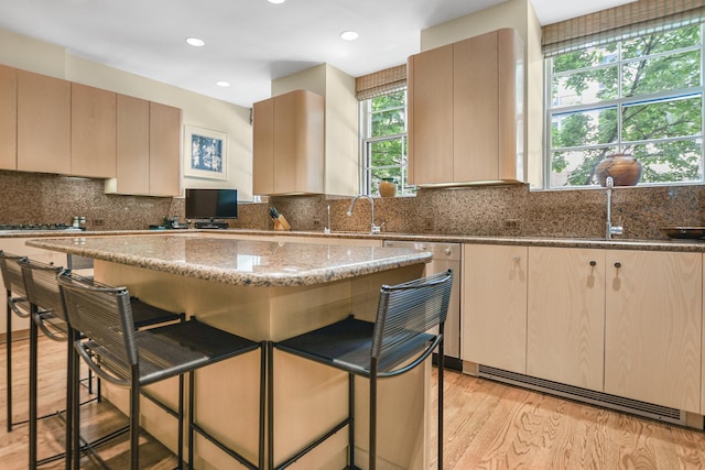 kitchen featuring a breakfast bar area, light wood-type flooring, and dark stone counters