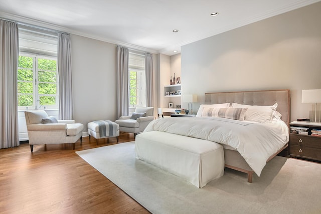 bedroom with ornamental molding, light hardwood / wood-style floors, and multiple windows