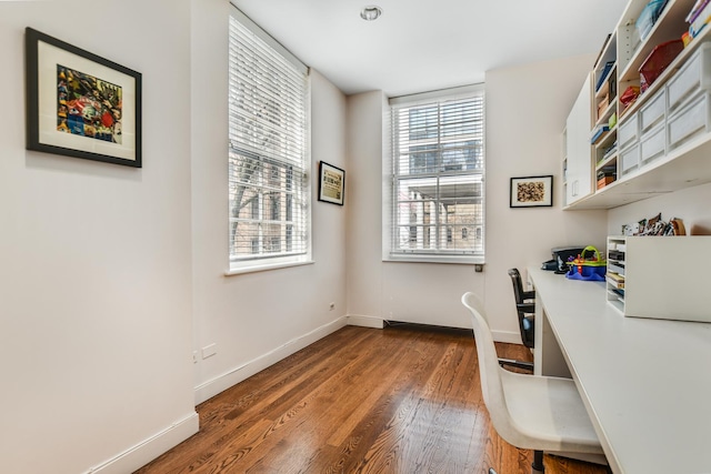 home office with dark hardwood / wood-style flooring and built in desk