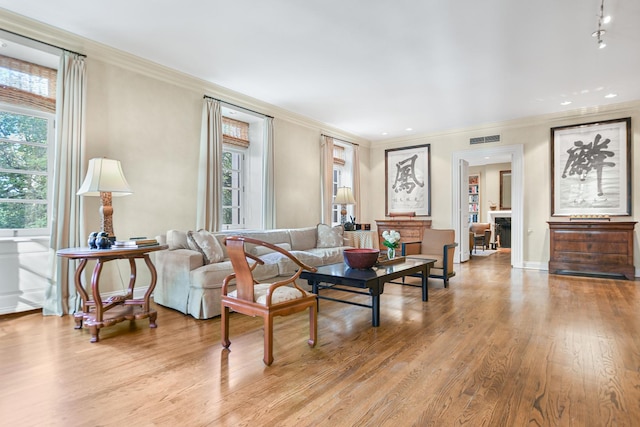 living room with crown molding, plenty of natural light, and light hardwood / wood-style flooring