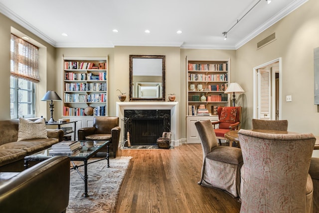 sitting room featuring a premium fireplace, crown molding, hardwood / wood-style floors, and built in shelves