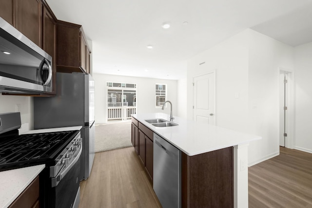 kitchen featuring an island with sink, appliances with stainless steel finishes, sink, and hardwood / wood-style floors