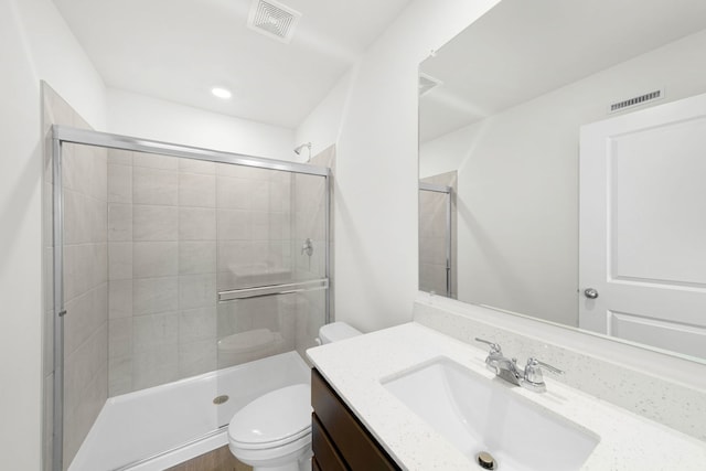 bathroom featuring vanity, toilet, and a shower with shower door