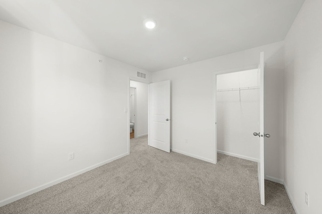 unfurnished bedroom with light colored carpet and a closet