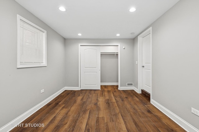 unfurnished bedroom with dark hardwood / wood-style flooring and a closet