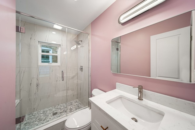 bathroom featuring a shower with door, vanity, and toilet