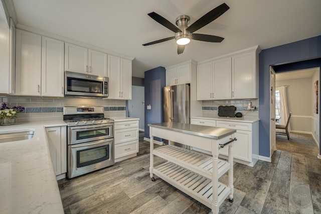 kitchen with stainless steel appliances, white cabinetry, hardwood / wood-style floors, and decorative backsplash