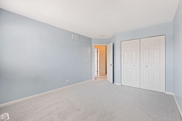 unfurnished bedroom featuring light carpet and a closet