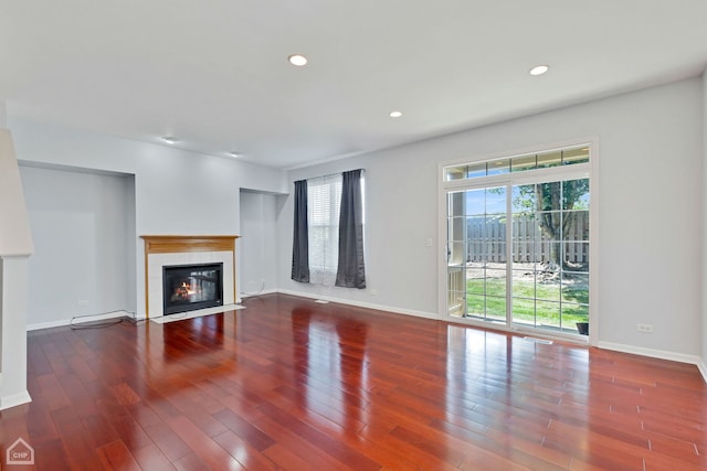 unfurnished living room with wood-type flooring and a tile fireplace