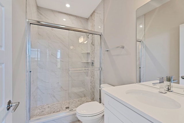 bathroom with vanity, a shower with shower door, and toilet