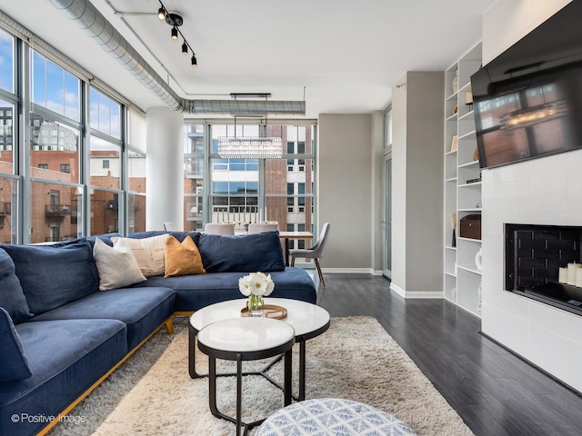 living room featuring expansive windows, a healthy amount of sunlight, rail lighting, and dark hardwood / wood-style floors