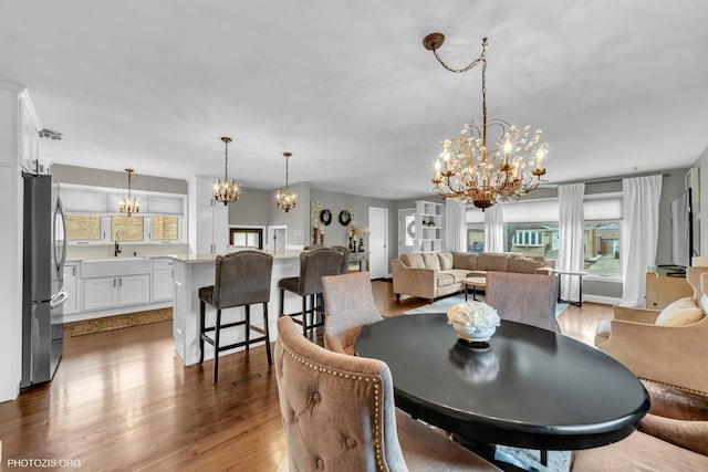 dining space with an inviting chandelier, sink, and hardwood / wood-style flooring