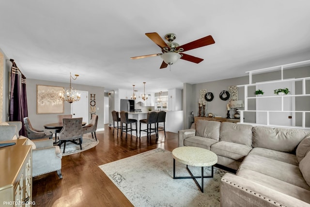 living room with dark hardwood / wood-style flooring and ceiling fan with notable chandelier