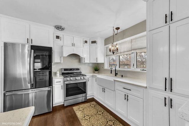 kitchen with pendant lighting, appliances with stainless steel finishes, sink, and white cabinets