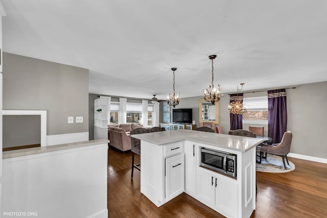 kitchen featuring dark hardwood / wood-style floors, white cabinetry, a kitchen bar, a center island, and an inviting chandelier