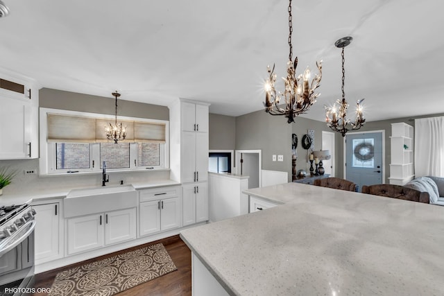 kitchen with sink, stainless steel gas range, an inviting chandelier, white cabinetry, and decorative light fixtures