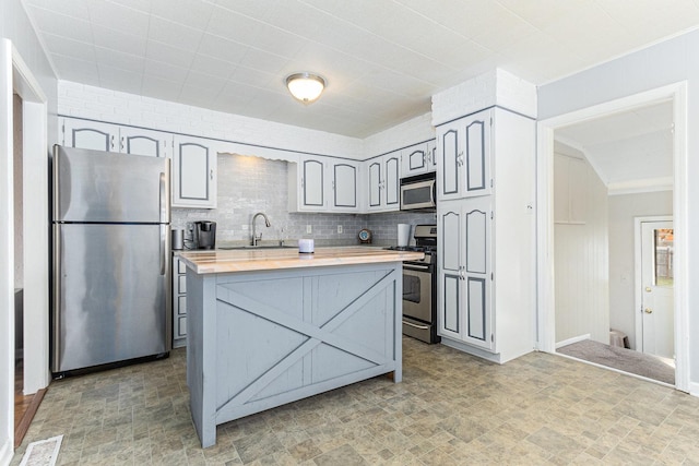 kitchen with sink, appliances with stainless steel finishes, butcher block counters, gray cabinetry, and tasteful backsplash