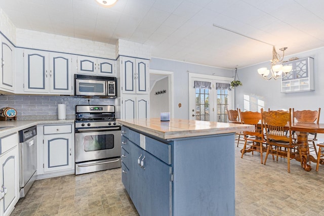 kitchen featuring pendant lighting, a chandelier, decorative backsplash, a center island, and stainless steel appliances