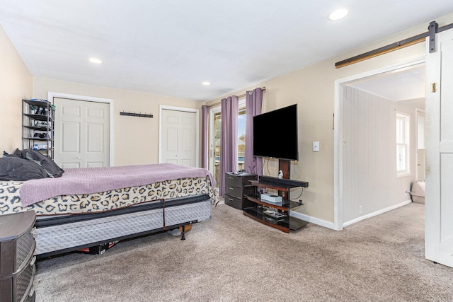 carpeted bedroom with multiple closets and a barn door