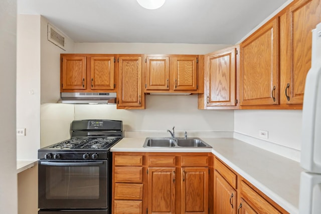 kitchen featuring white refrigerator, sink, and black gas range oven