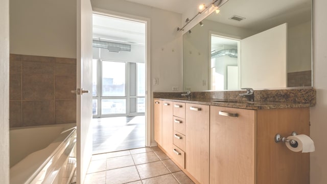 bathroom featuring tile patterned flooring, a sink, visible vents, double vanity, and a bathtub