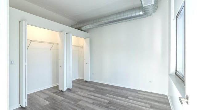 unfurnished bedroom with a closet, visible vents, baseboards, and wood finished floors