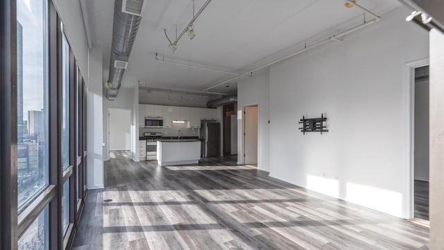 unfurnished living room with visible vents, dark wood-type flooring, a sink, and rail lighting