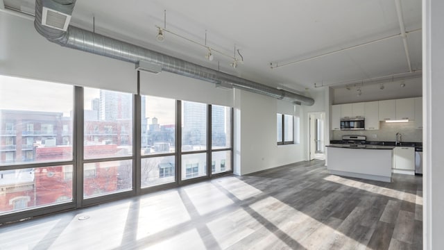 interior space featuring a city view, stainless steel appliances, dark countertops, white cabinets, and wood finished floors