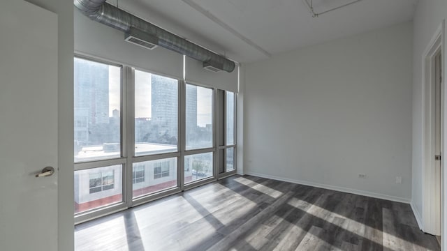 empty room featuring visible vents, baseboards, and dark wood finished floors