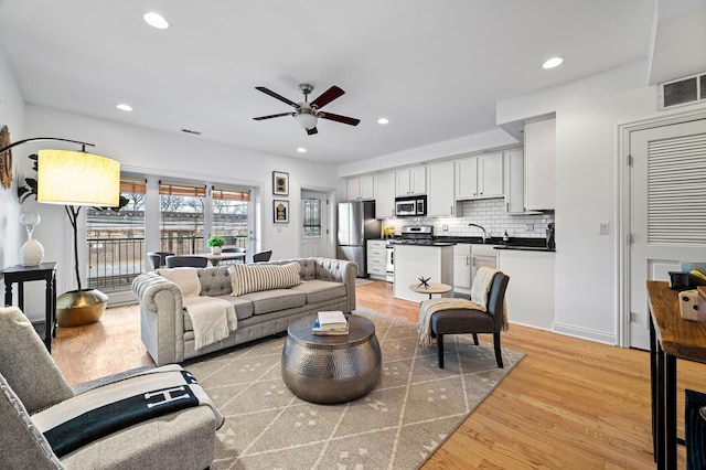 living room with sink, ceiling fan, and light wood-type flooring