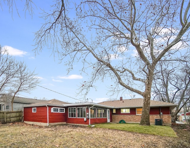 rear view of house with cooling unit, a yard, and a sunroom