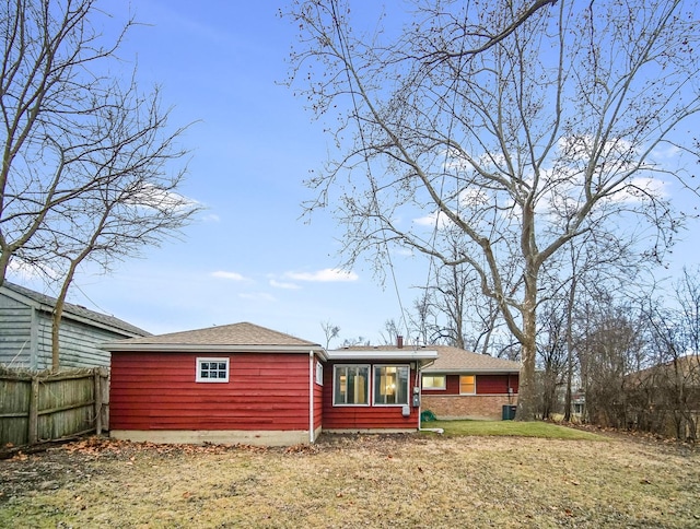 rear view of house with central AC unit and a yard