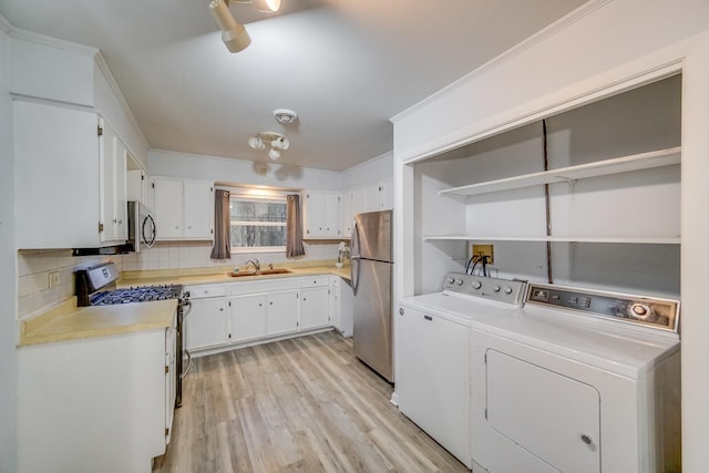 kitchen featuring tasteful backsplash, white cabinetry, sink, stainless steel appliances, and washing machine and dryer