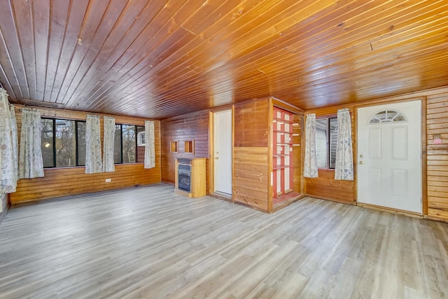 unfurnished living room with wood-type flooring, wooden ceiling, and wooden walls