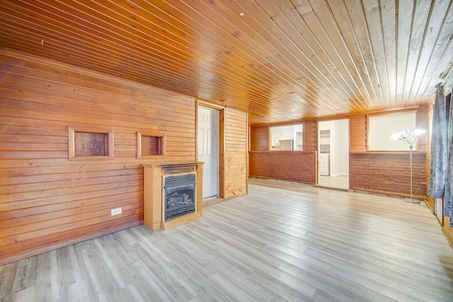 unfurnished living room featuring wood ceiling, wooden walls, a fireplace, and light wood-type flooring