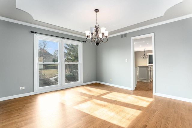 unfurnished room featuring crown molding, light wood-type flooring, and a chandelier