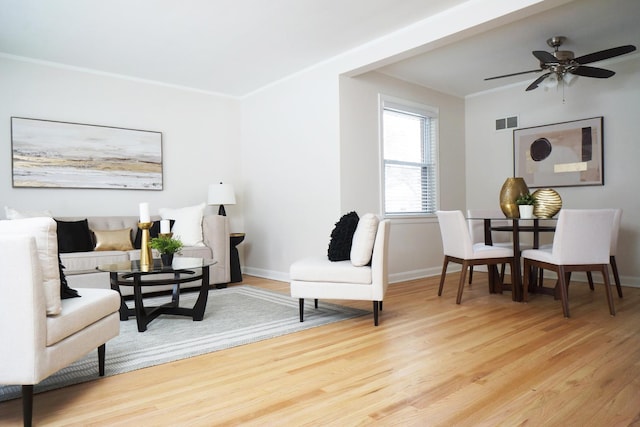 living area with ceiling fan, ornamental molding, and wood-type flooring