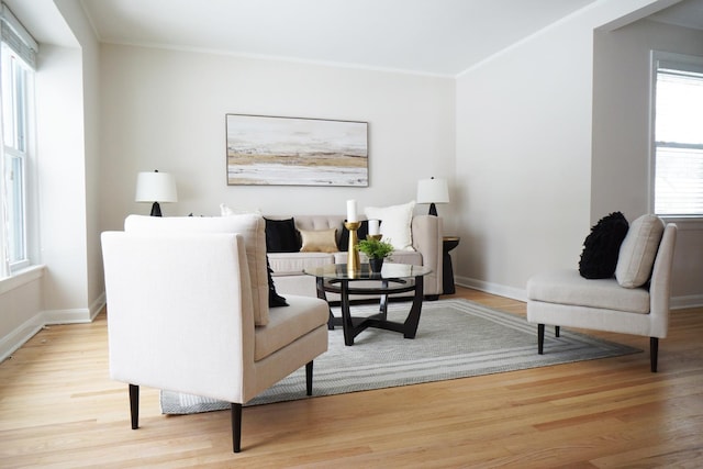 living area with crown molding and light wood-type flooring