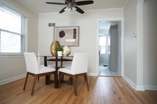 dining space featuring ornamental molding, a wealth of natural light, and light hardwood / wood-style flooring