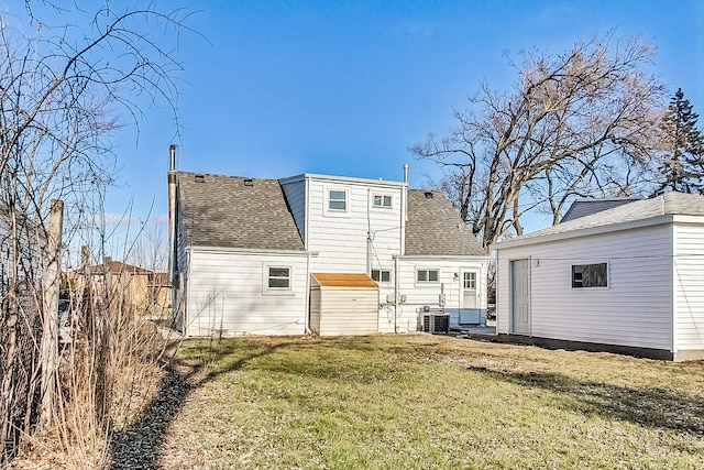 rear view of house with an outbuilding, a lawn, and central air condition unit