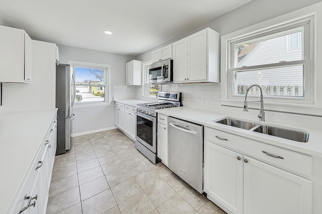 kitchen with sink, light tile patterned floors, white cabinets, stainless steel appliances, and backsplash